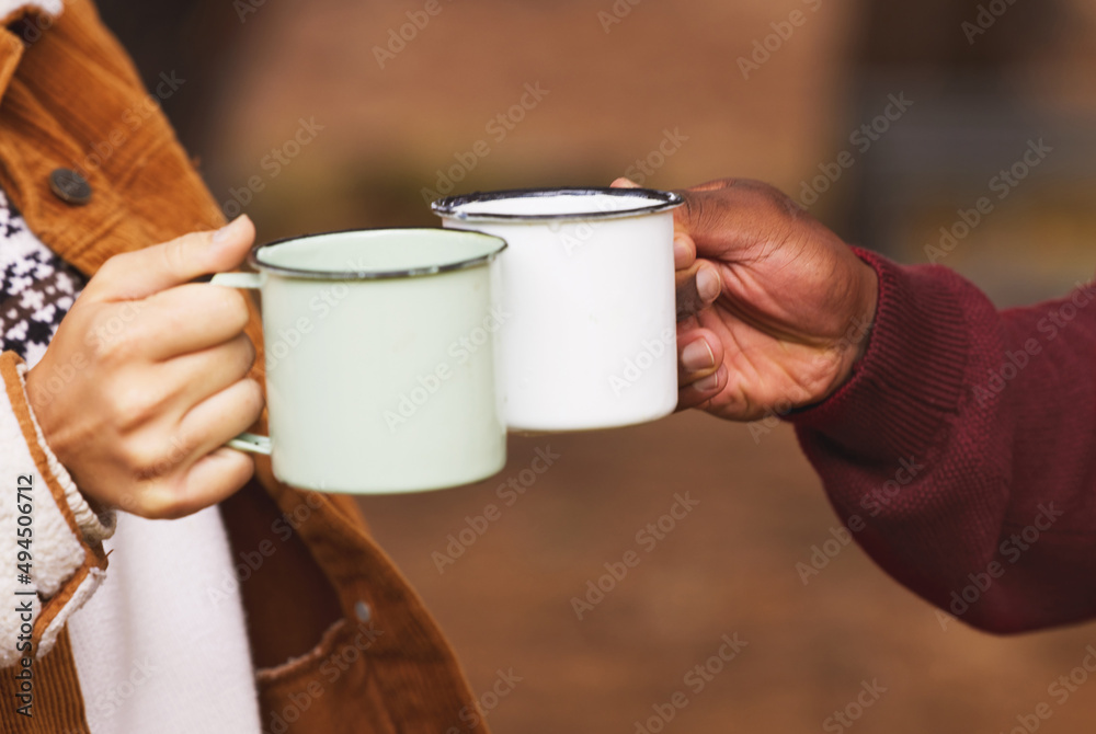 让我们热身吧。一对夫妇在外面用咖啡杯烤面包的镜头