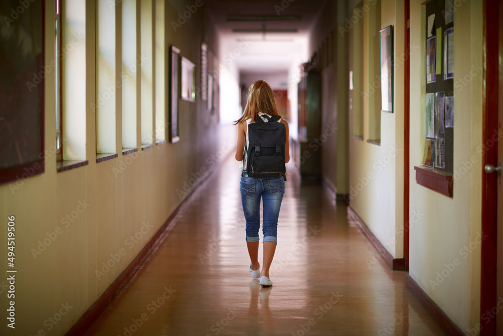 该回家了。一个年轻女孩在学校走廊上的照片。