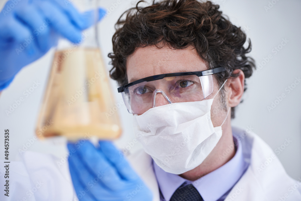 What could this mean. A cropped shot of a scientist examining a flask filled with liquid.