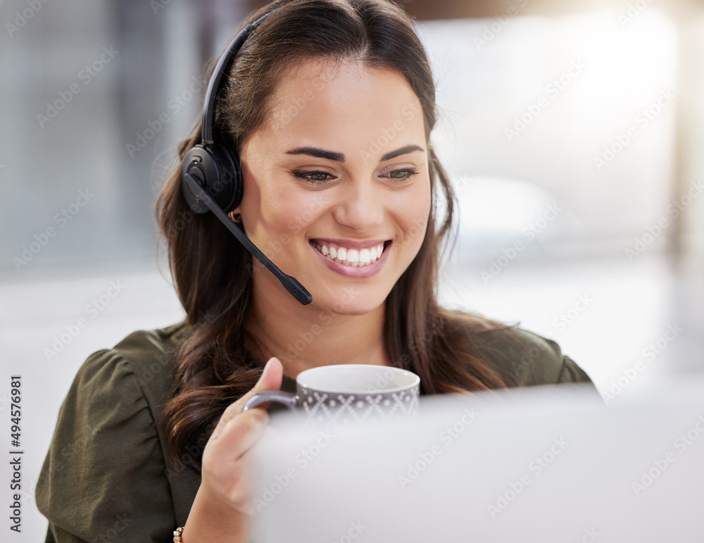 Getting through another successful day. Shot of a young call centre agent drinking coffee while work