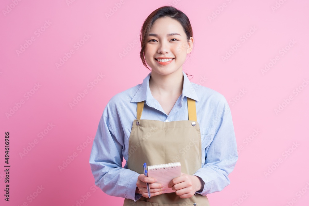 站在粉色背景上的年轻亚洲女服务员