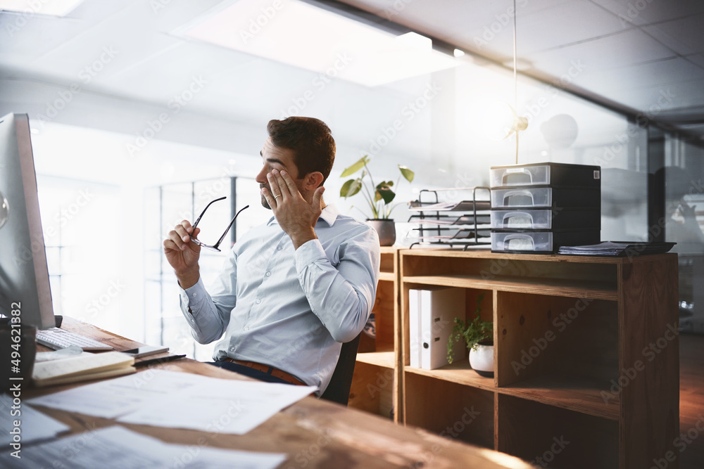 Trying his best to stay awake to make the deadline. Shot of a young businessman looking exhausted wh