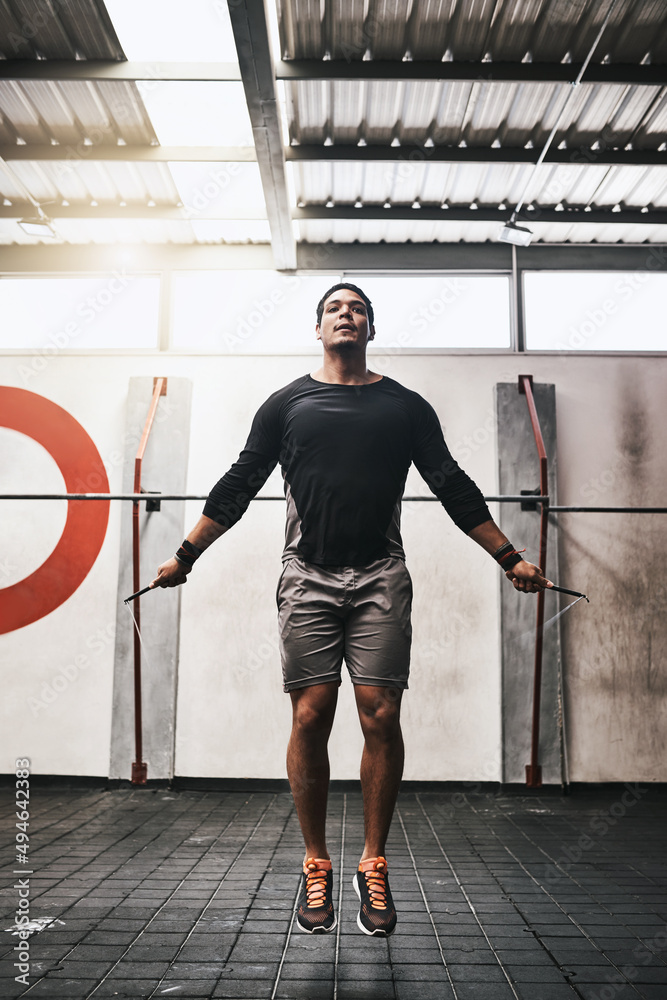 Getting closer to his fitness goals. Shot of a young man skipping rope in a gym.