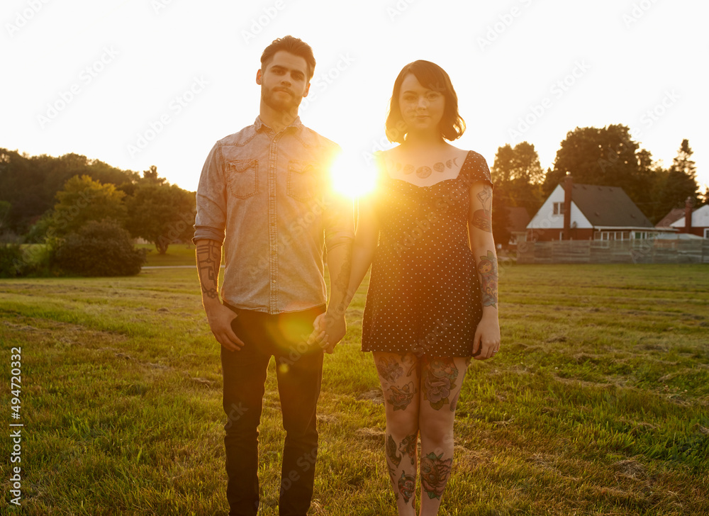 Tattoosstatements of their love. Portrait of a young couple holding hands outdoors.