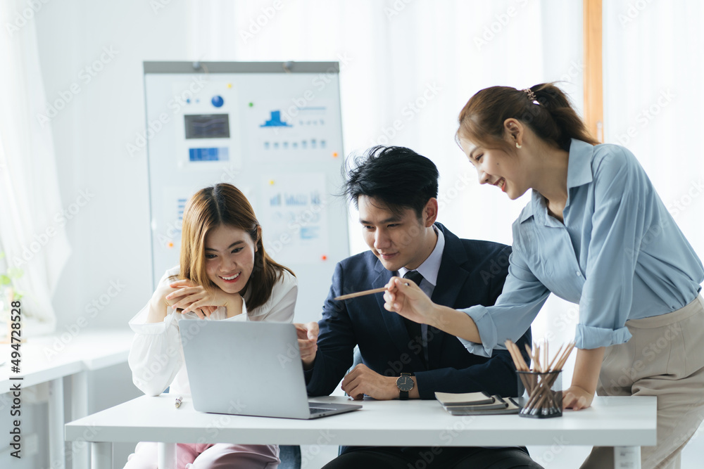 Cheerful asian people colleagues working together sit at desk look at computer screen discuss new pr