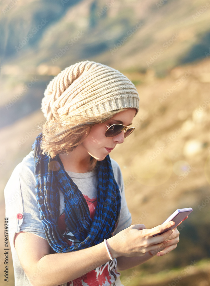 Connected in the wilderness. Cropped shot of a teenage girl sending a text message outdoors.