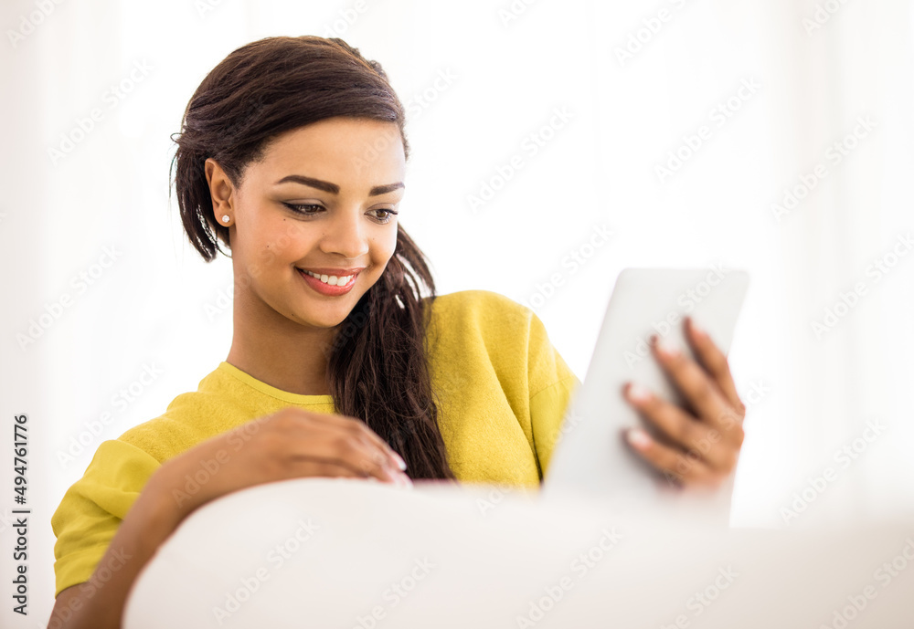 Checking out some funny pics online. Shot of a young woman using a digital tablet at home.