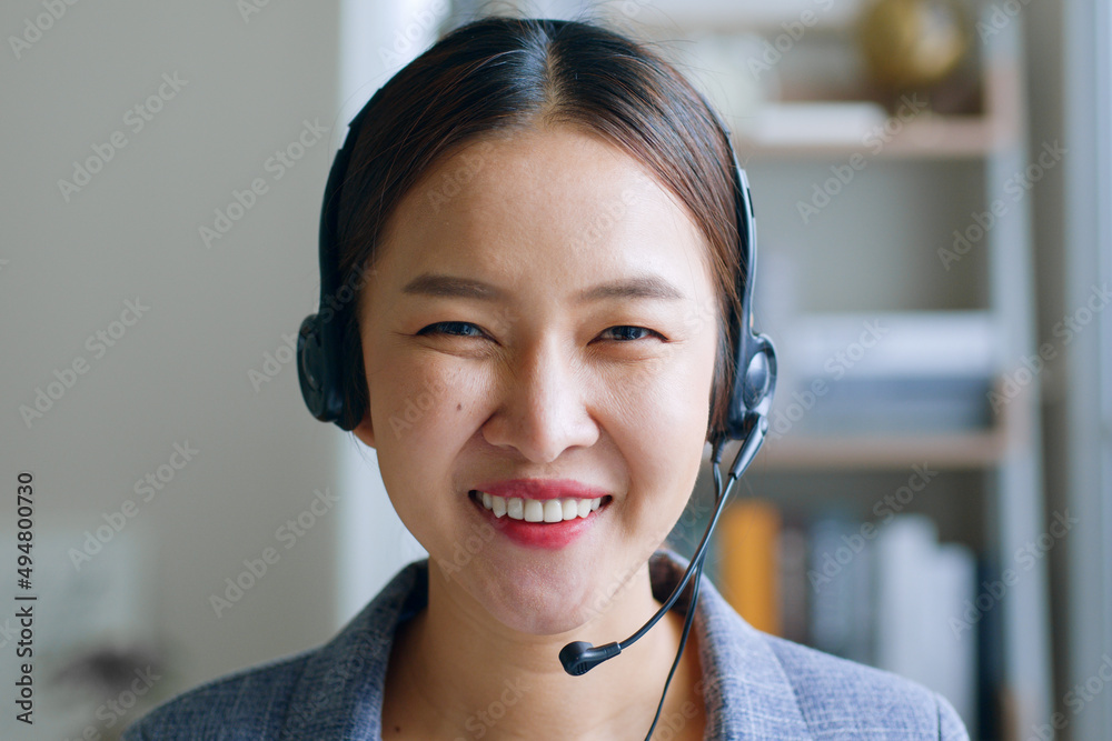 Close up of Young Asian businesswoman, call center, customer service wearing headphone and smiling. 