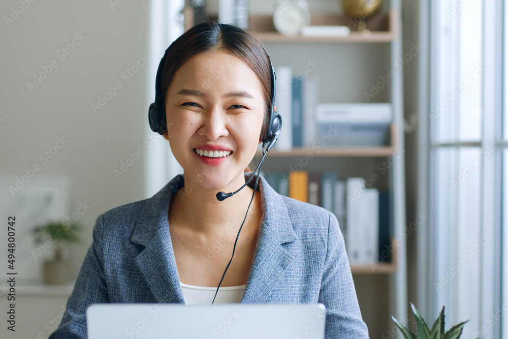 Young Asian businesswoman, call center, customer service wearing headphone and smiling. Look at came