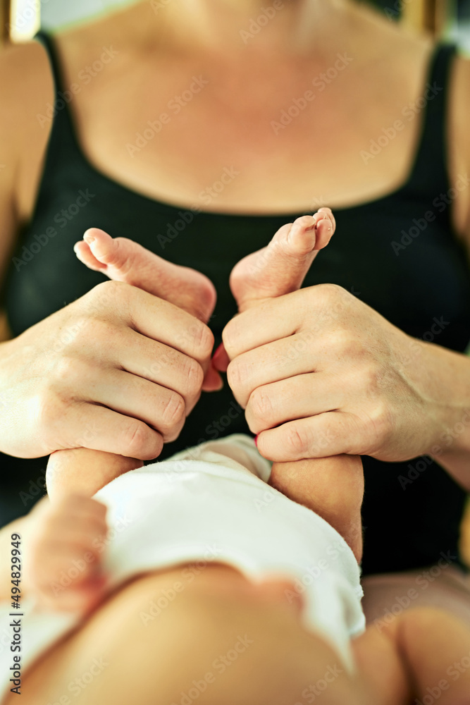 Look at these little feet. Shot of a unrecognisable mother holding her little baby boys legs while h