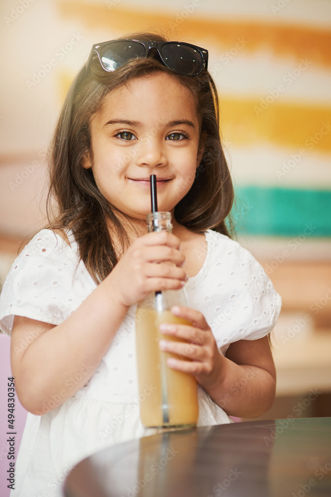 So refreshing. Shot of an adorable little girl enjoying a cold drink in a cafe.