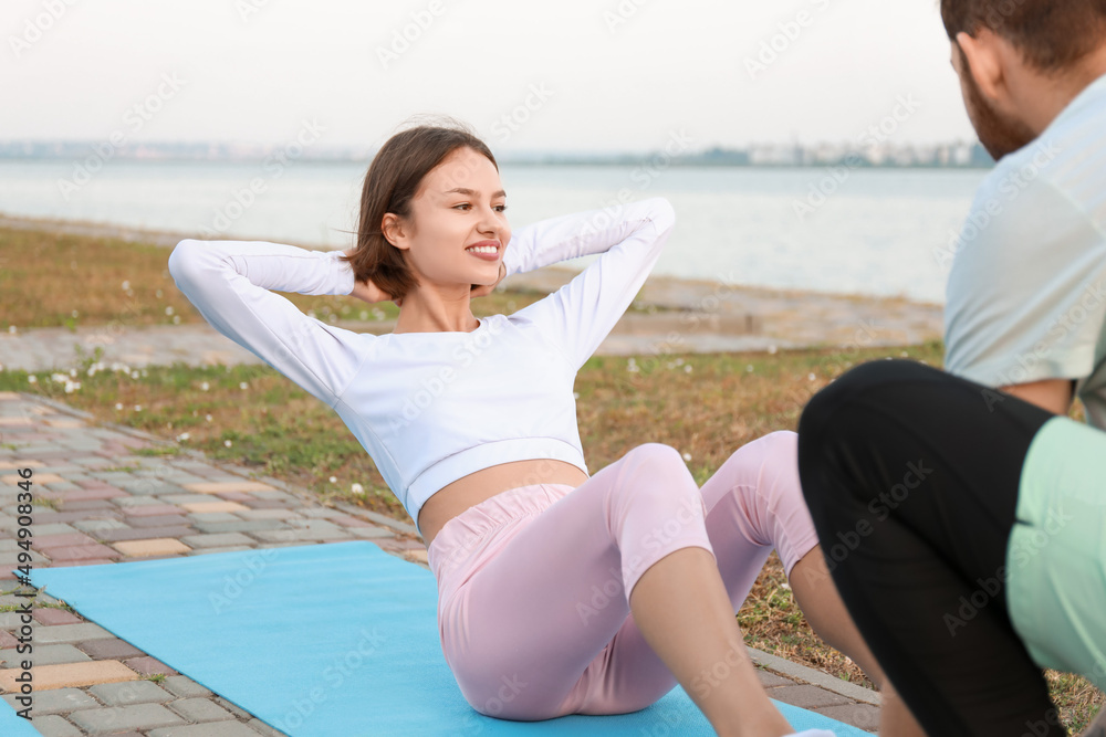 Sporty young woman training with her boyfriend near river