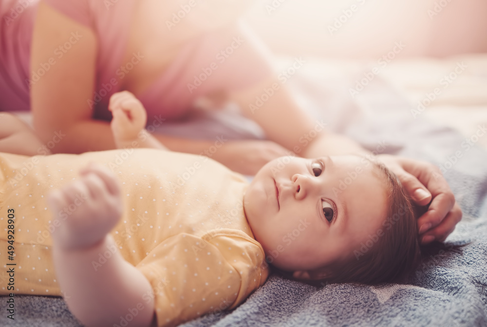 Happy mother with cute baby in bedroom.