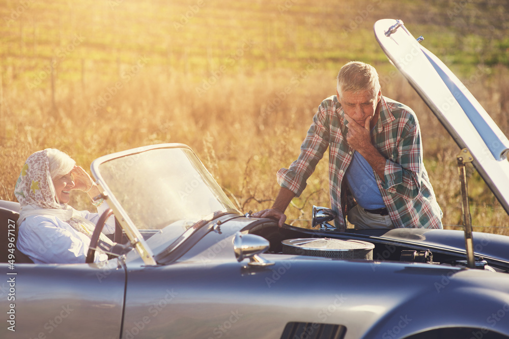 Roadtrip car trouble. Shot of a senior man looking under the hood of his car while on a roadtrip wit