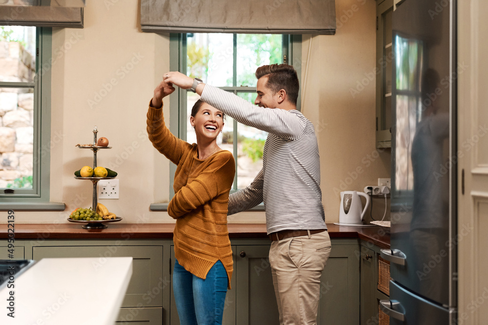 Shes forever his princess. Shot of an affectionate young couple dancing together in their kitchen at