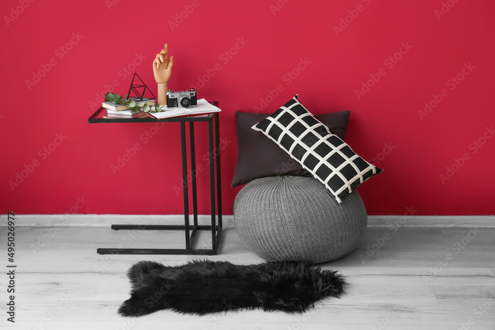 Modern pouf and table near color wall in room