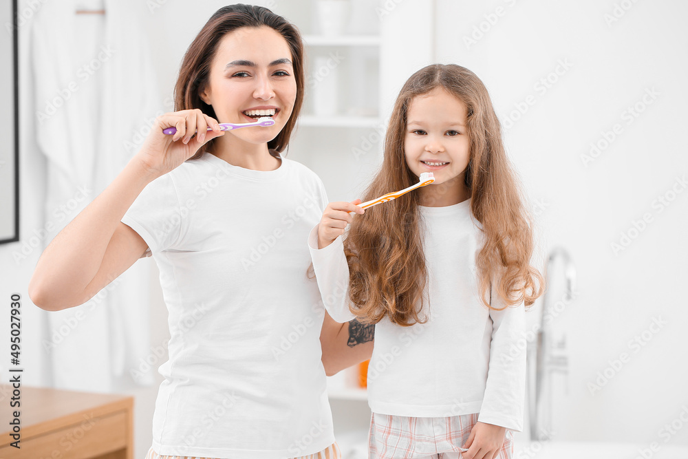 Little girl with her mother brushing teeth in bathroom