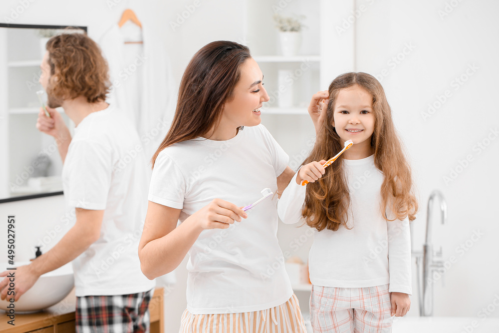 Little girl with her mother brushing teeth in bathroom