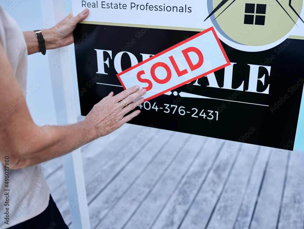 Another property sold. High angle shot of an unrecognizable female real estate agent sticking a sold