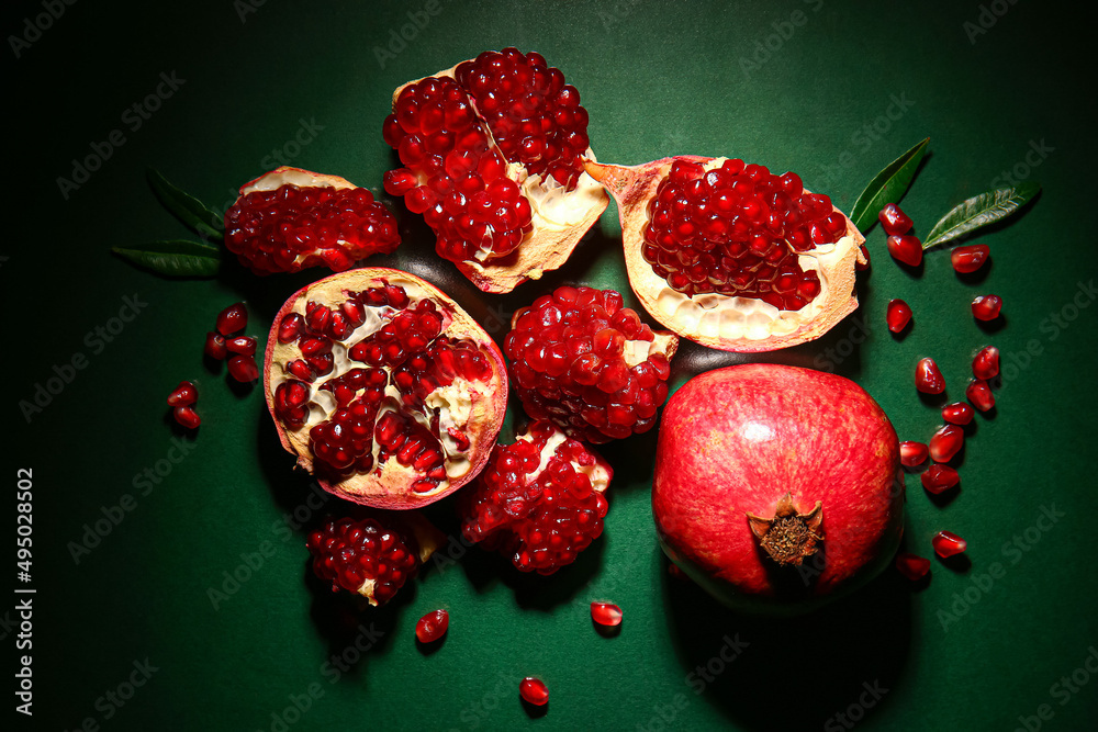 Tasty ripe pomegranates on dark green background