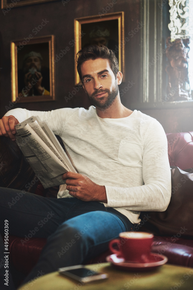 Getting my daily fill of coffee and news. Portrait of a handsome man reading a newspaper in a cafe.