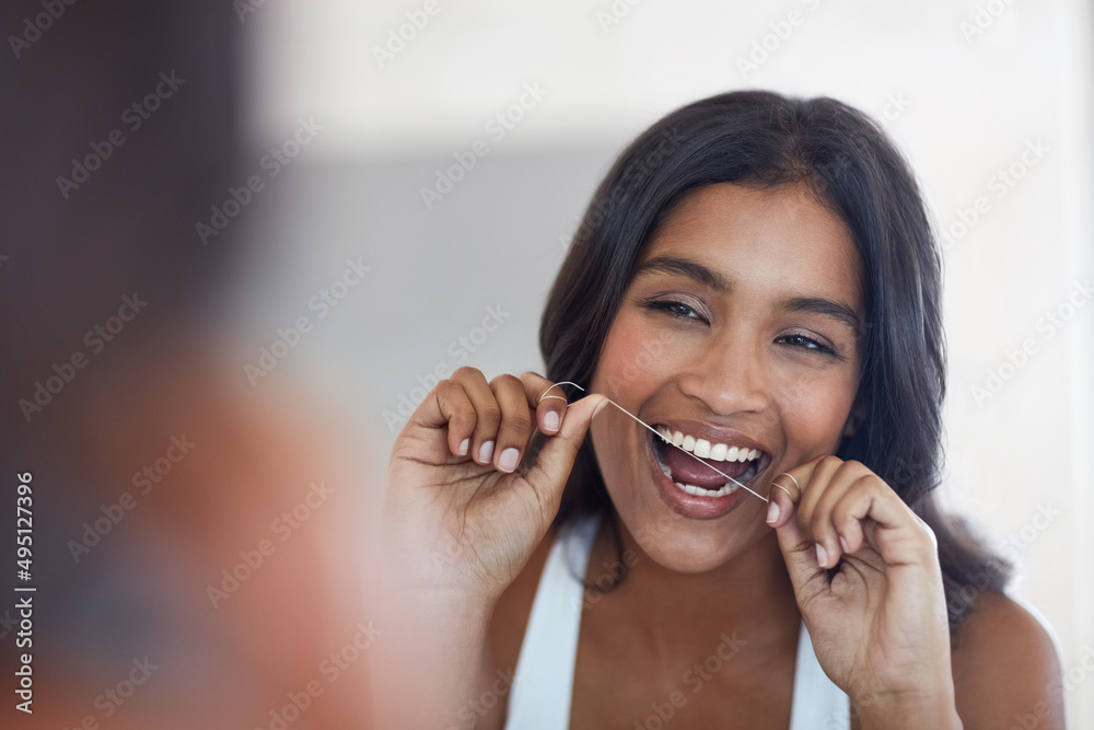 你的牙齿在很大程度上决定了你的健康。一位迷人而快乐的年轻女子用牙线擦拭T恤的照片