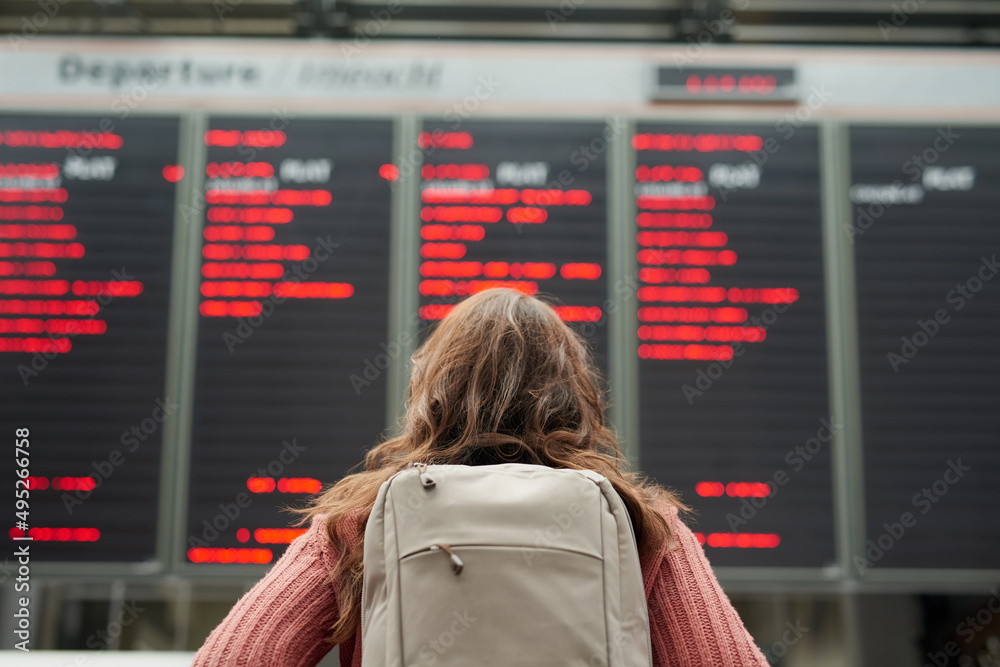 Looking for her flight. Rearview shot of an unrecognizable young woman standing in an airport.