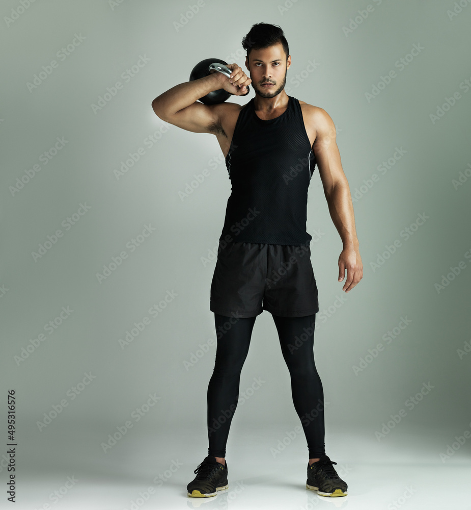 Proud of the body I worked for. Studio shot of a young man working out with a kettle bell against a 