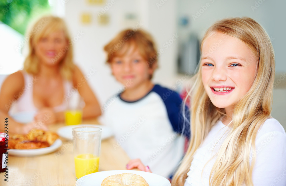 Smiling little girl with her family having breakfast. Portrait of a smiling little girl with her fam