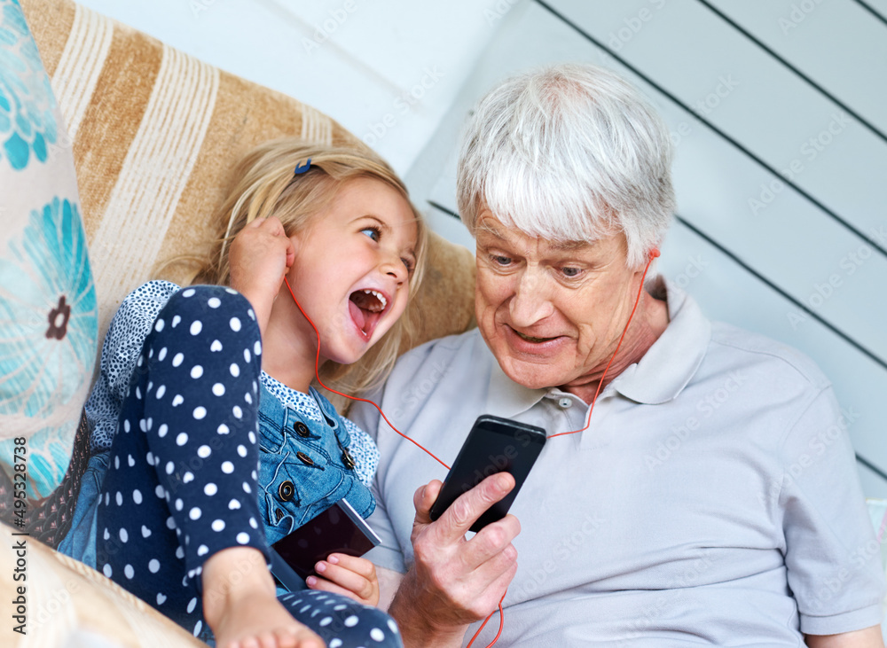 Listen to this. Shot of an adorable little girl listening to music from a cellphone with her grandfa