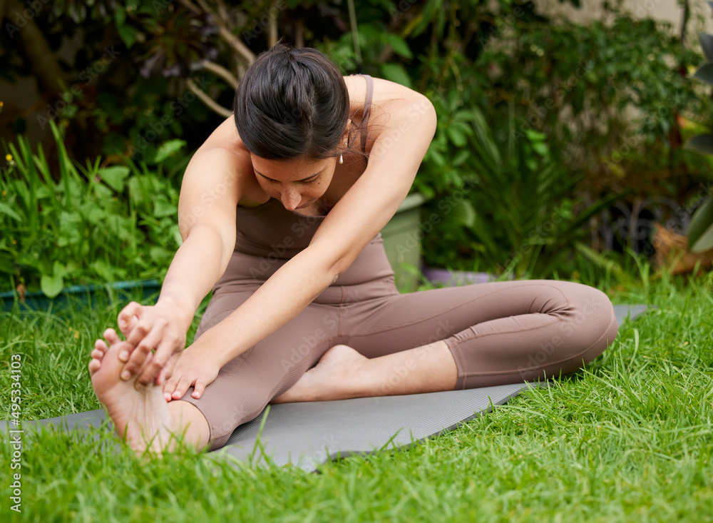 Regular movement is good for your body. Shot of a young woman stretching her legs while exercising o