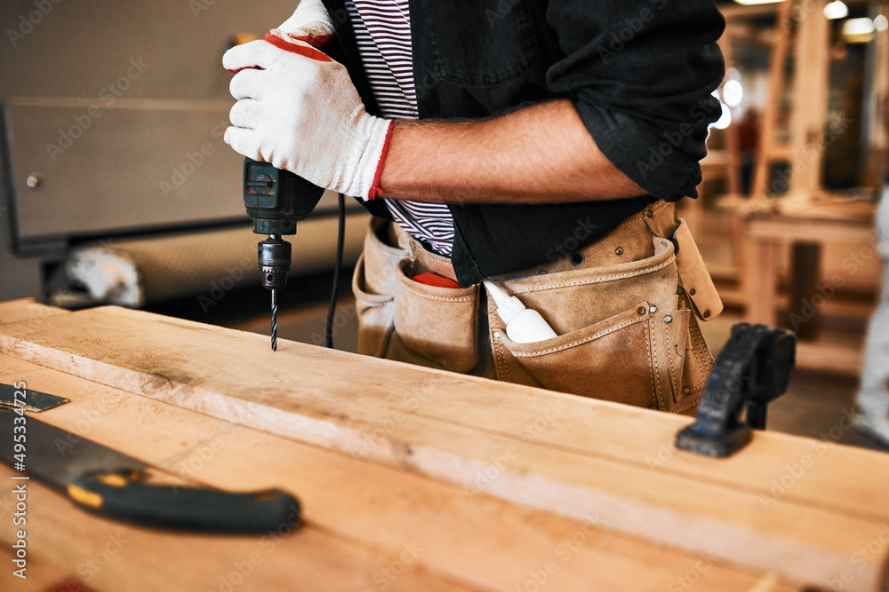 Its all apart of the drill. Cropped shot of an unrecognizable carpenter using an electric drill insi