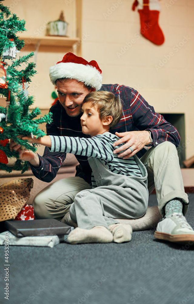 I see my name on that one. Shot of an adorable little boy sitting next to the Christmas tree with hi