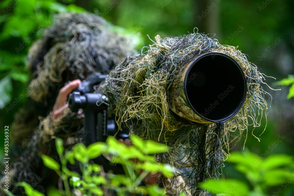 Wildlife photographer in the summer ghillie camouflage suit