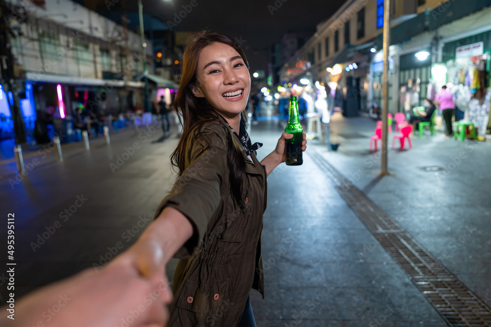 亚洲女旅行者的肖像，牵着男朋友的手，走在街上