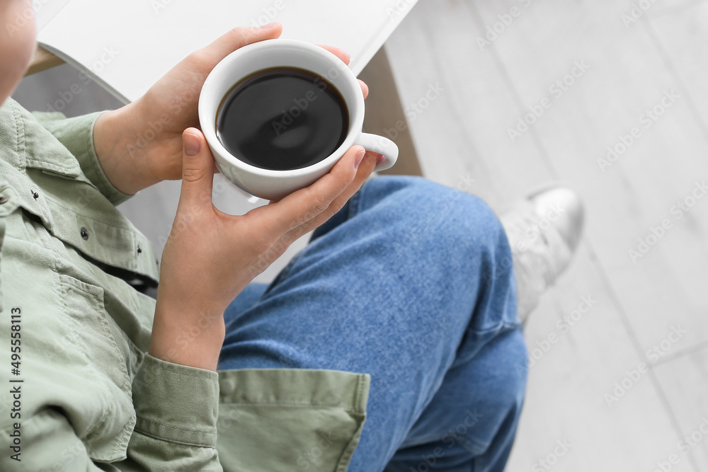 厨房里拿着一杯热咖啡的年轻女人，特写