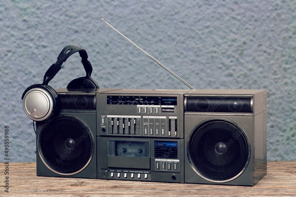 Retro boombox outdated portable black radio receiver with a cassette recorder on the desk