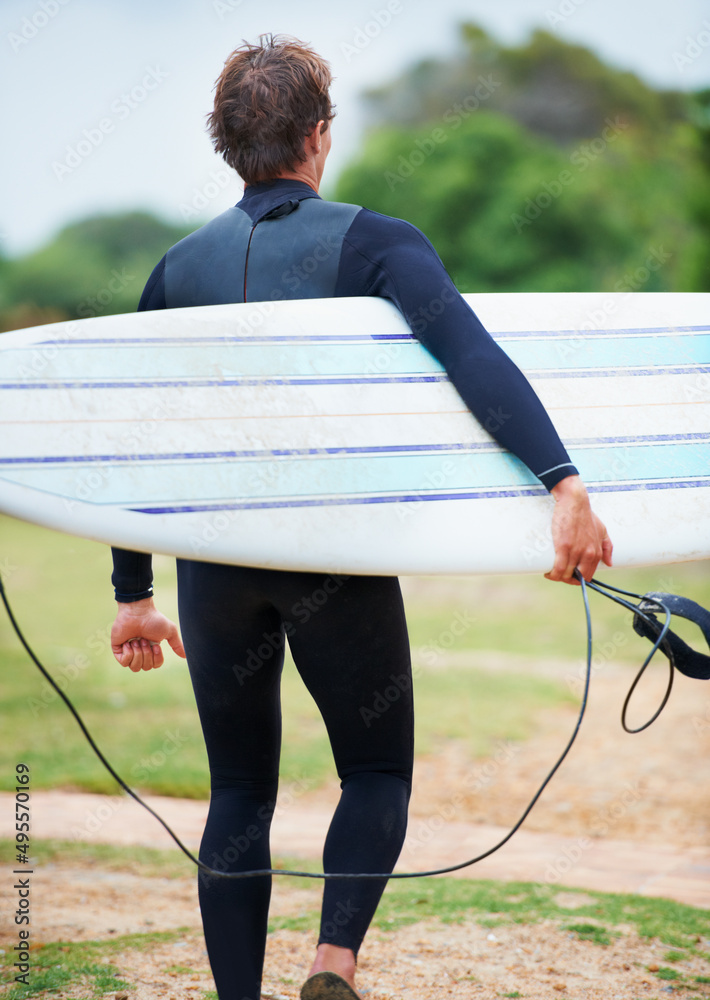 Surfing is a lifestyle. A surfer carrying his board on his way to the beach.