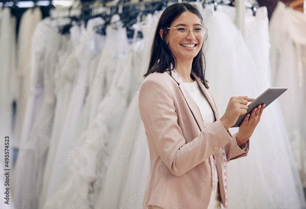 You can browse our dresses online or in-store. Shot of a seamstress using a digital tablet while wor