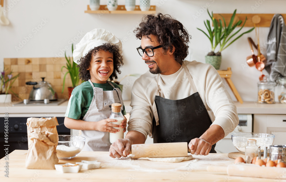 Positive black father and son cooking together