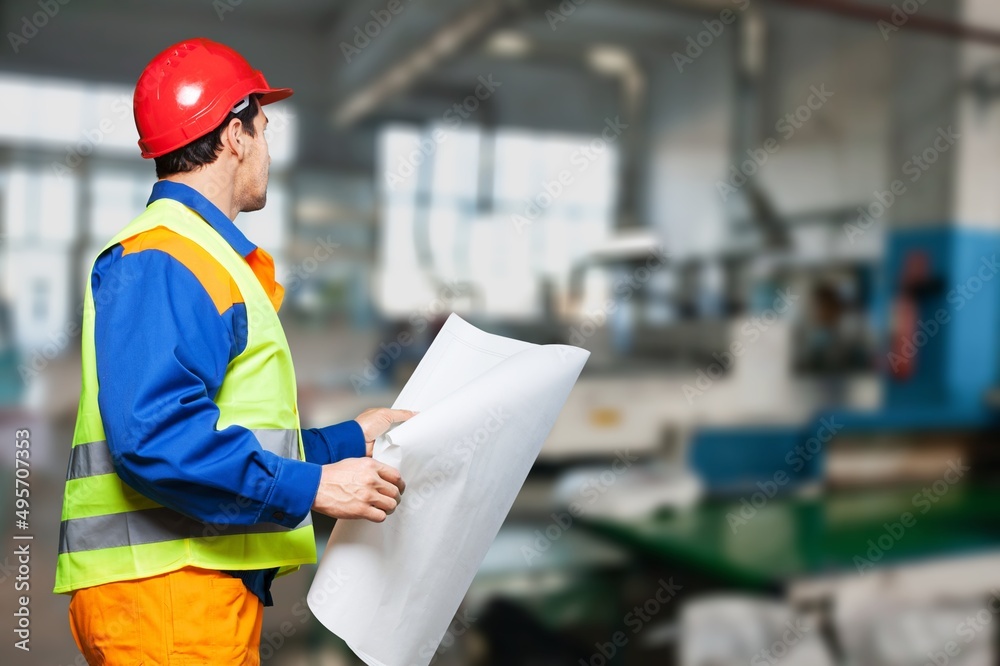 Architect man wearing helmet hard hat holding paper drawing template, checking construction plan.