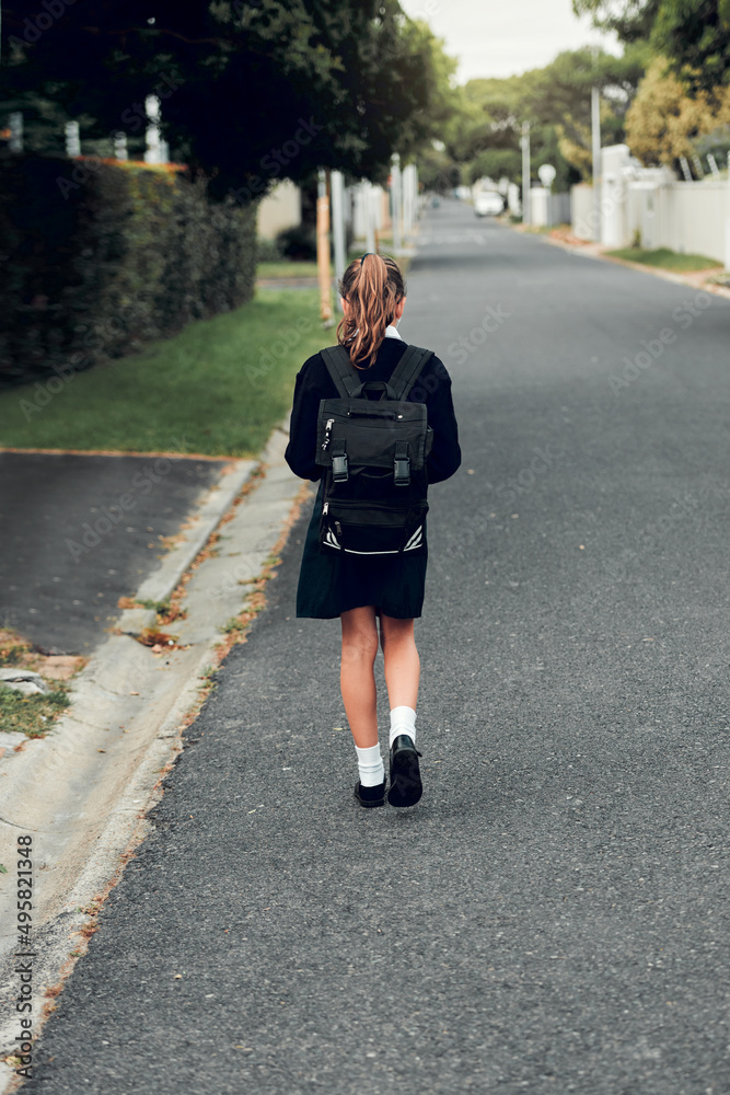 教育是我们为改善未来而走的路。年轻女学生走向的后视镜头