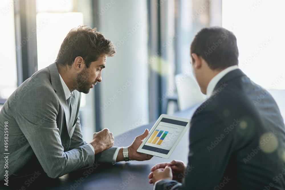 Looking for ways to increase profits. Shot of two colleagues looking at a graph on a digital tablet 