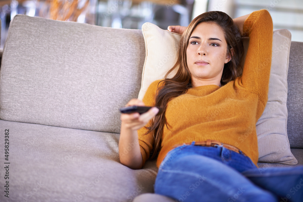 Channel surfing is all Im doing today.... Cropped shot of an attractive young woman changing TV chan