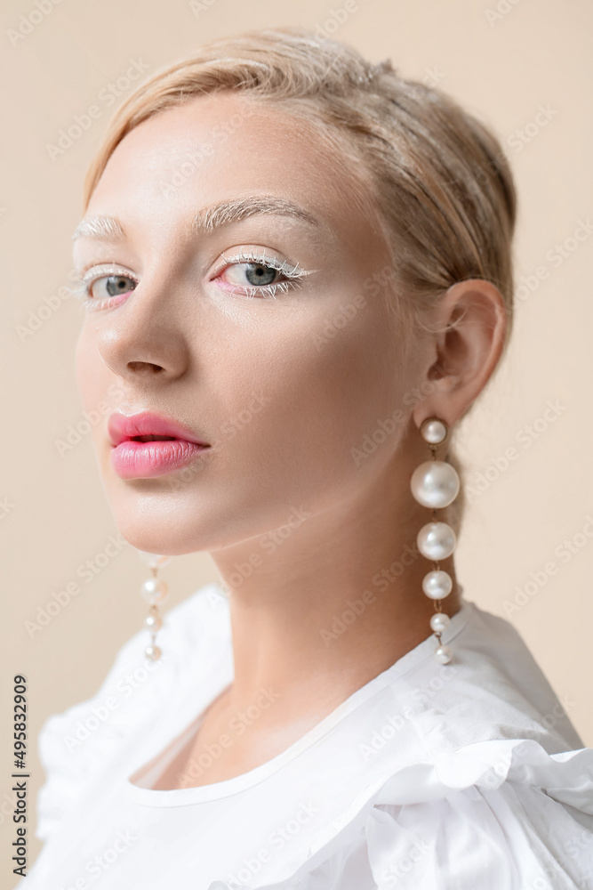 Beautiful young woman with creative makeup and stylish earrings on light background