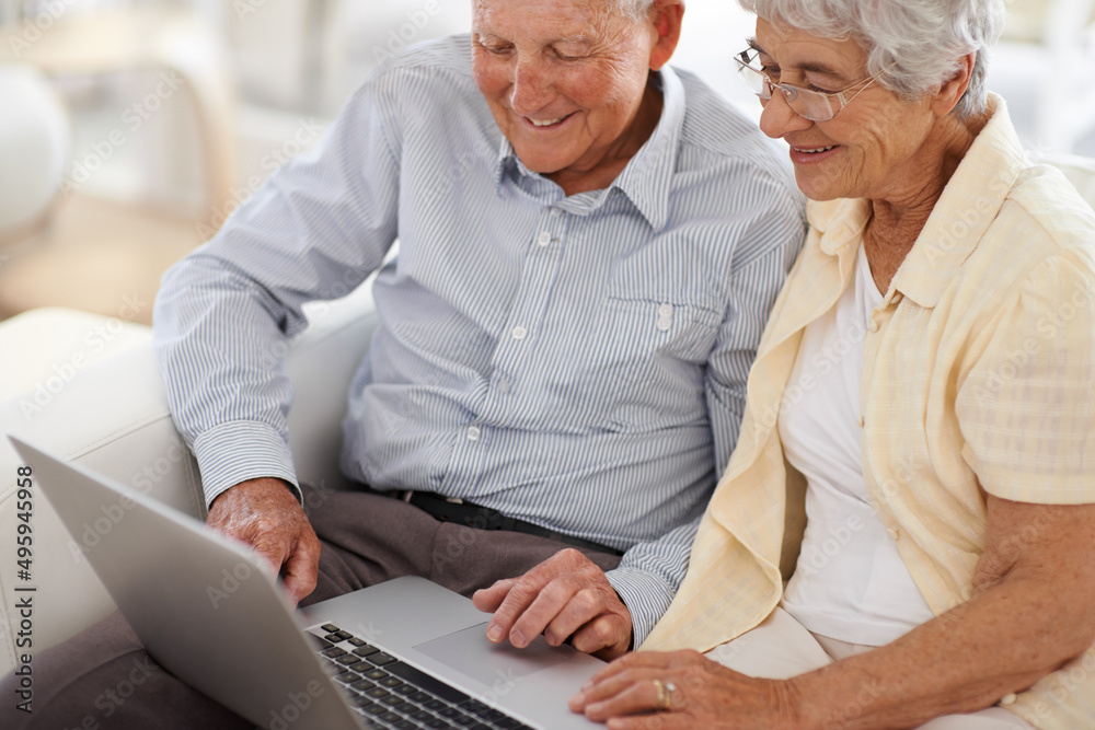 Getting to know technology together. An aged couple at home using a laptop.