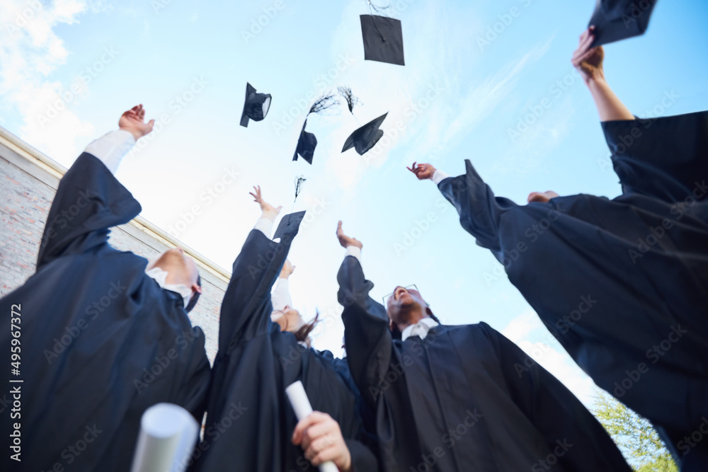 To the next chapter of our lives. Low angle shot of a group of students throwing their caps into the