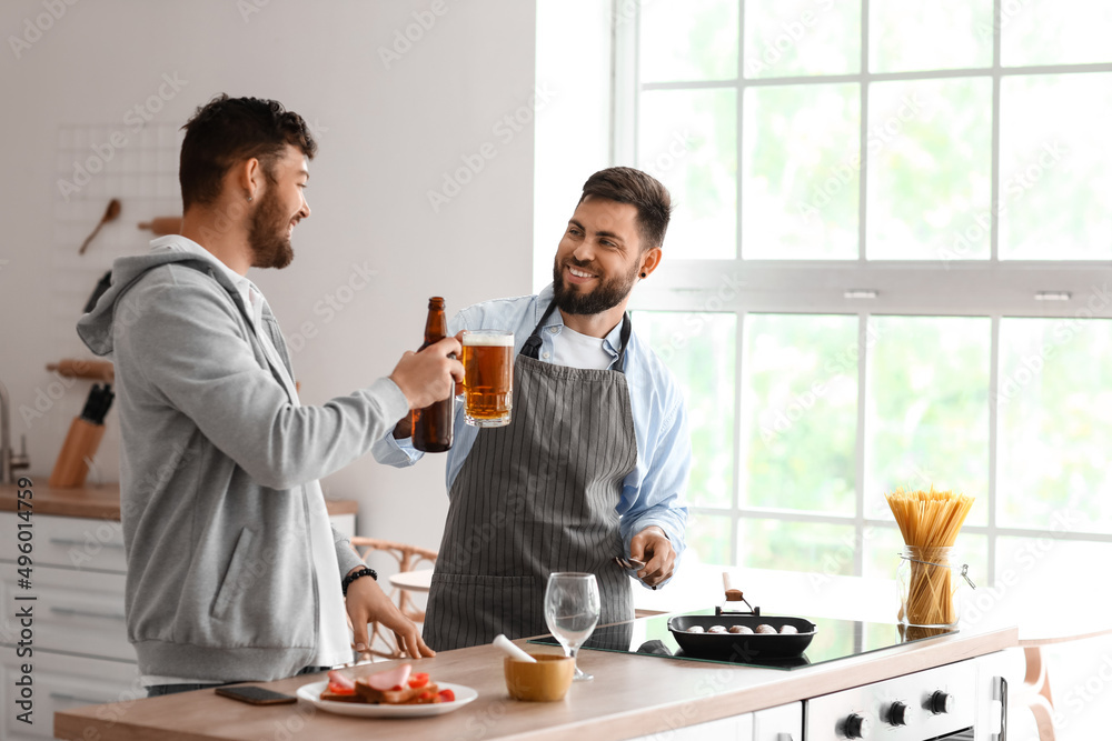 Young brothers drinking beer in kitchen