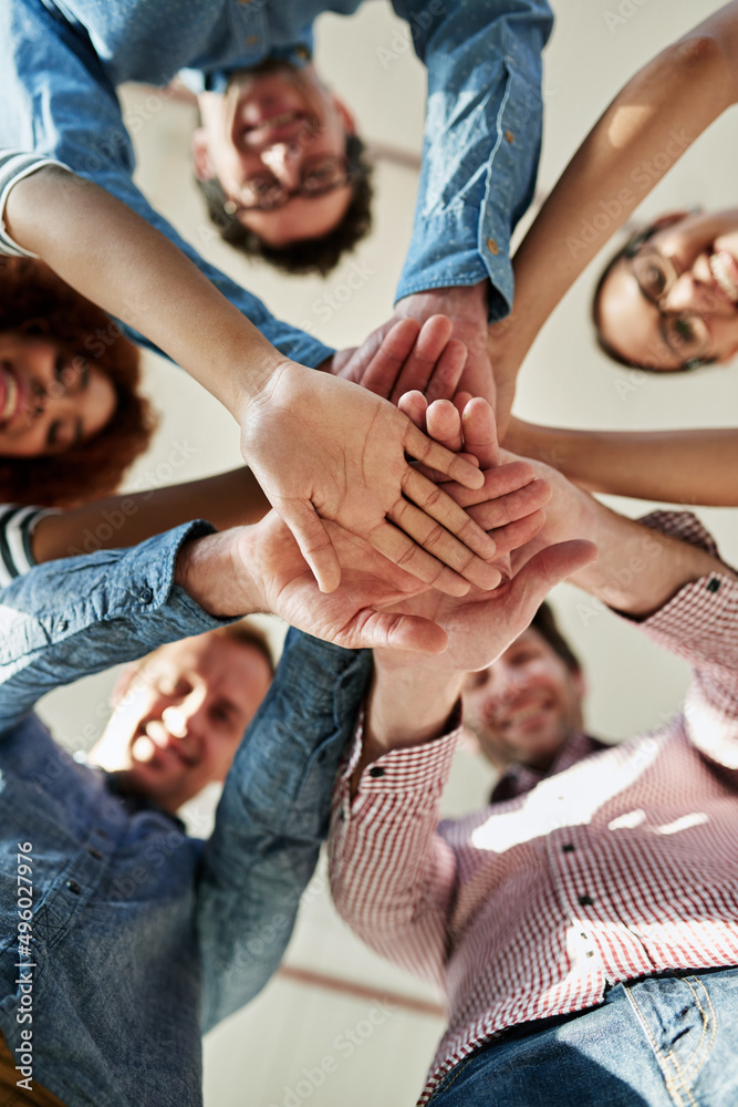 In it to succeed. Low angle portrait of a group of smiling coworkers in a huddle.