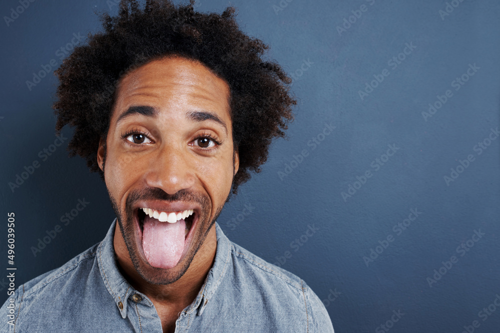 Cant hide the excitement. Portrait of a happy young man sticking his tongue out on a gray background